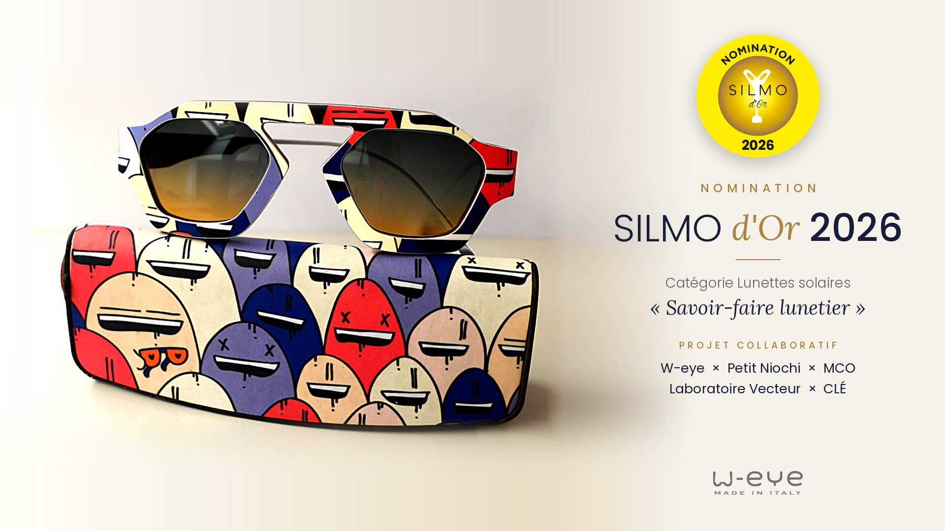 Lunettes solaires Kingfisher en bois peint, W-eye × Petit Niochi, posées sur leur étui illustré : nomination SILMO d'Or 2026, catégorie Lunettes solaires, « Savoir-faire lunetier »