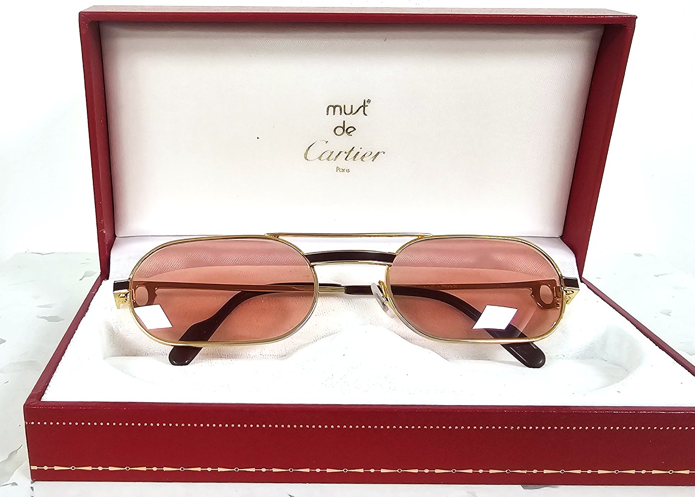 Lunettes Must de Cartier vintage, or et laque bordeaux, verres rosés, dans leur écrin rouge d'origine, chez MCO à Metz